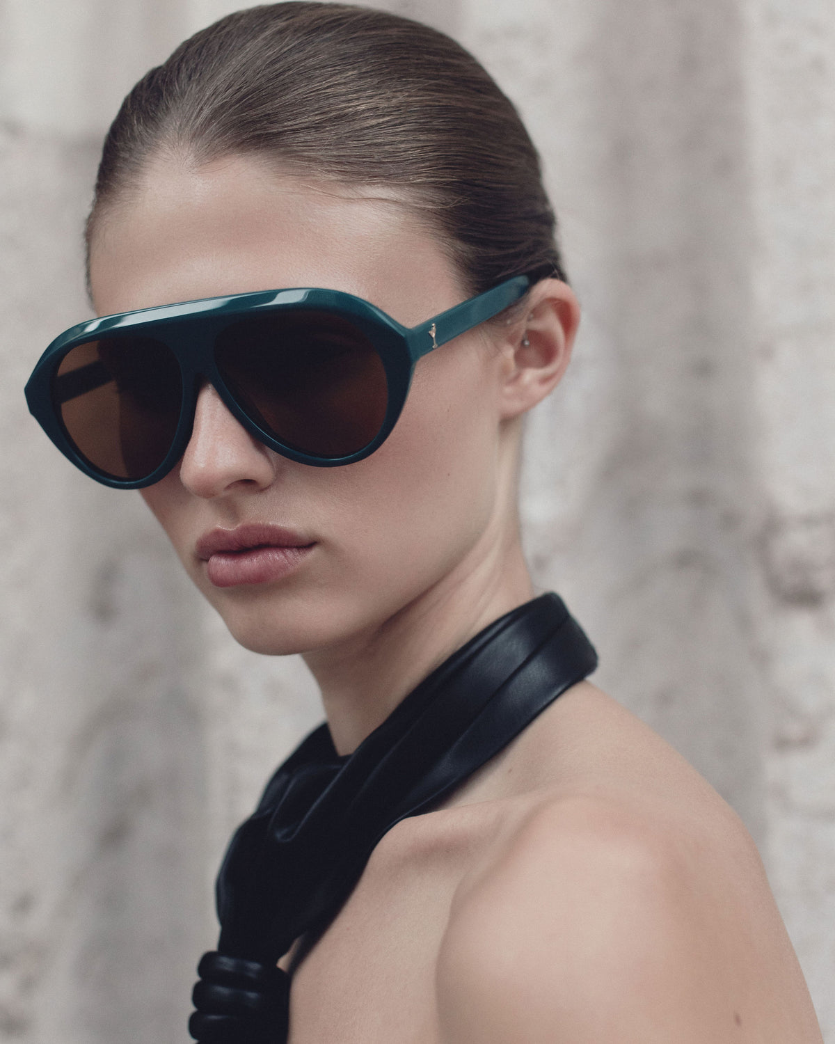 Model in Past Midnight The Icon Retrofête Sarcelle teal shield sunglasses with amber lenses and a black halter