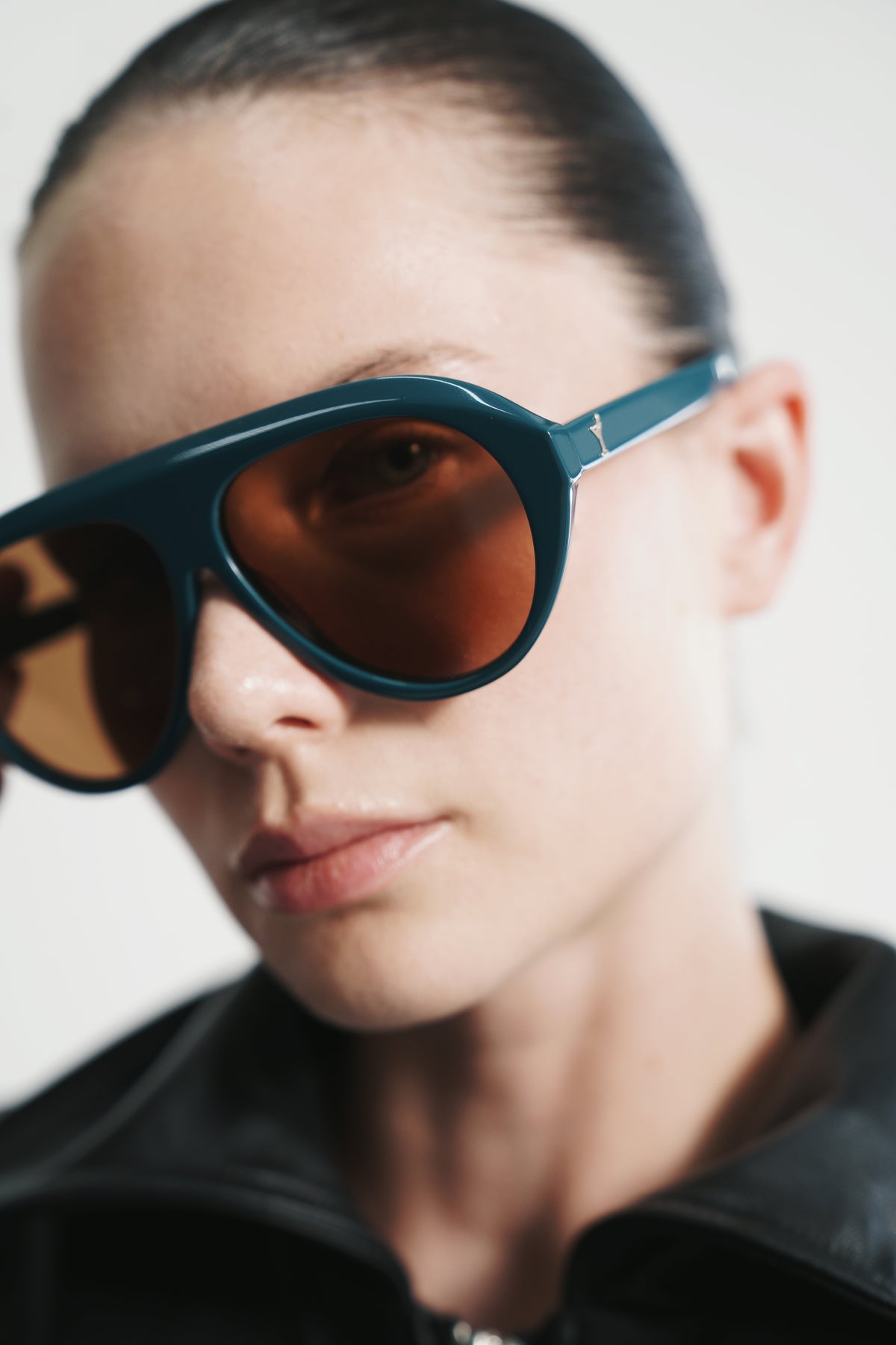 Three-quarter portrait in Retrofête x Past Midnight The Icon Sarcelle sunglasses with amber lenses and a black leather jacket