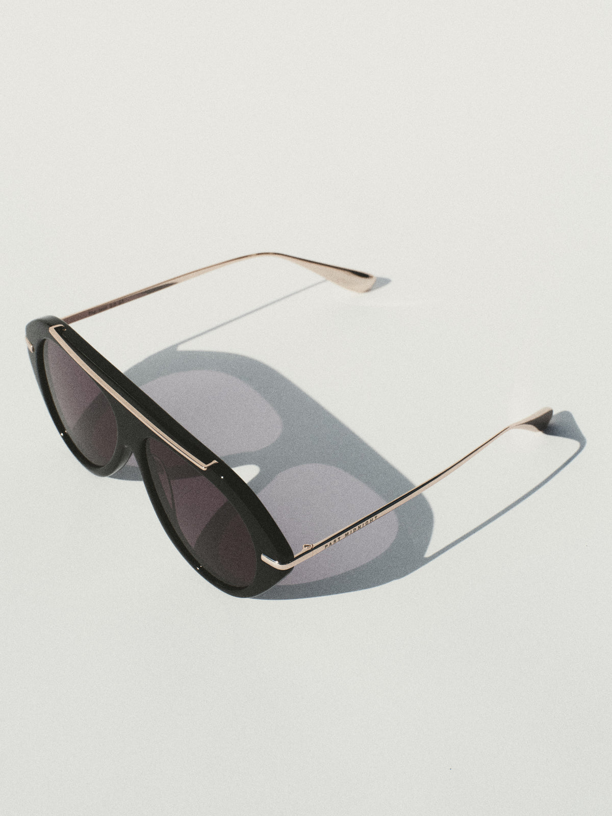 Past Midnight The Icon 2.0 Black shield sunglasses with gold brow bar and metal temples, angled still life