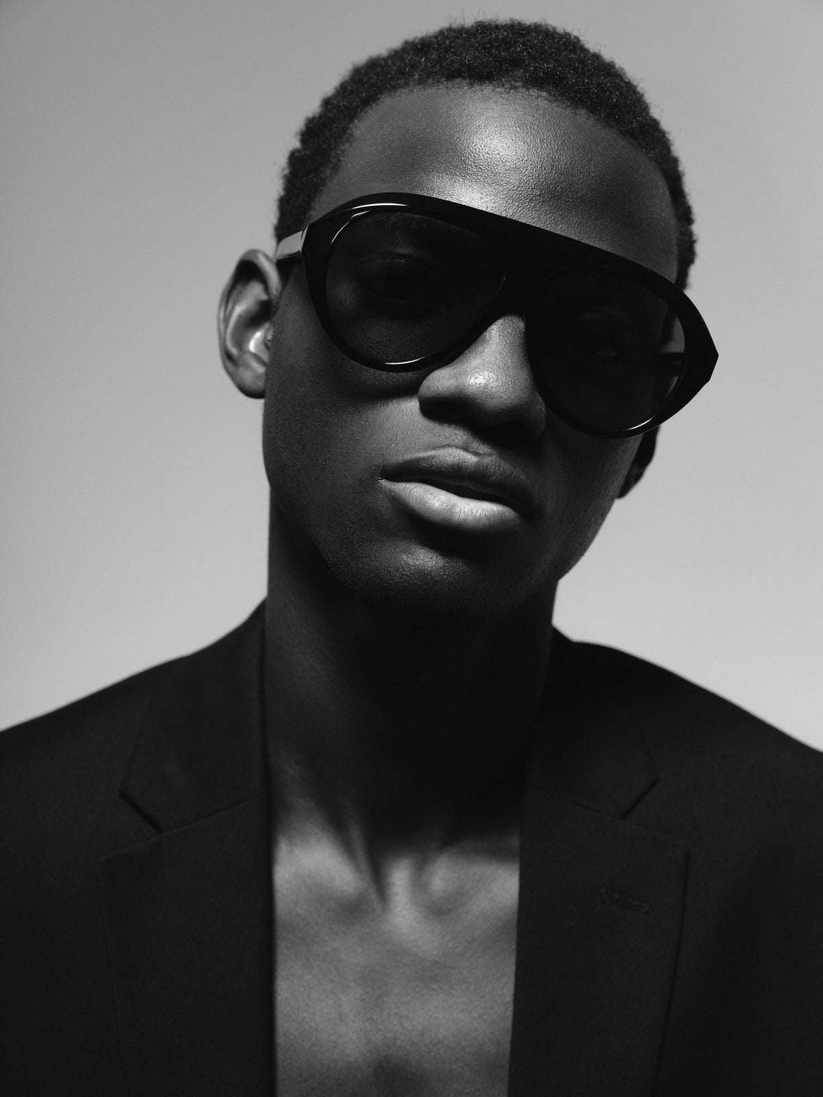 Black and white portrait of a man in a black blazer wearing Past Midnight shield sunglasses